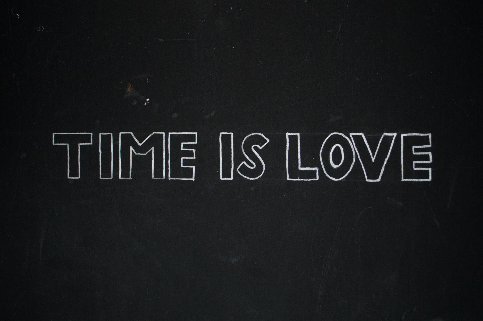 &ldquo;An image of &ldquo;TIME IS LOVE&rdquo;, written in all caps in white paint marker on a black wall.&rdquo;